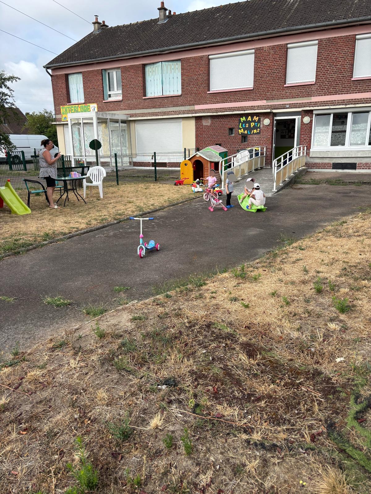 Façade extérieure de la MAM Les P'ti Malins et sa cour où jouent les enfants en plein air